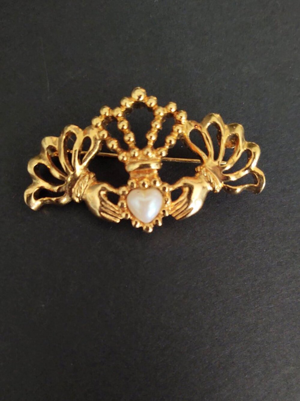 Gold hands holding faux pearl heart brooch